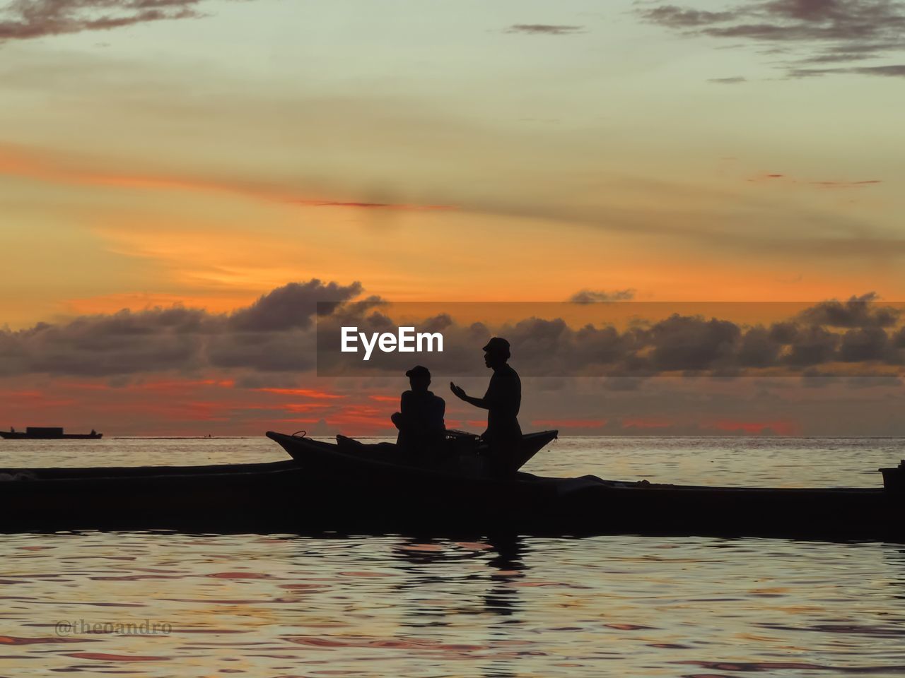 Silhouette men in sea against sky during sunset