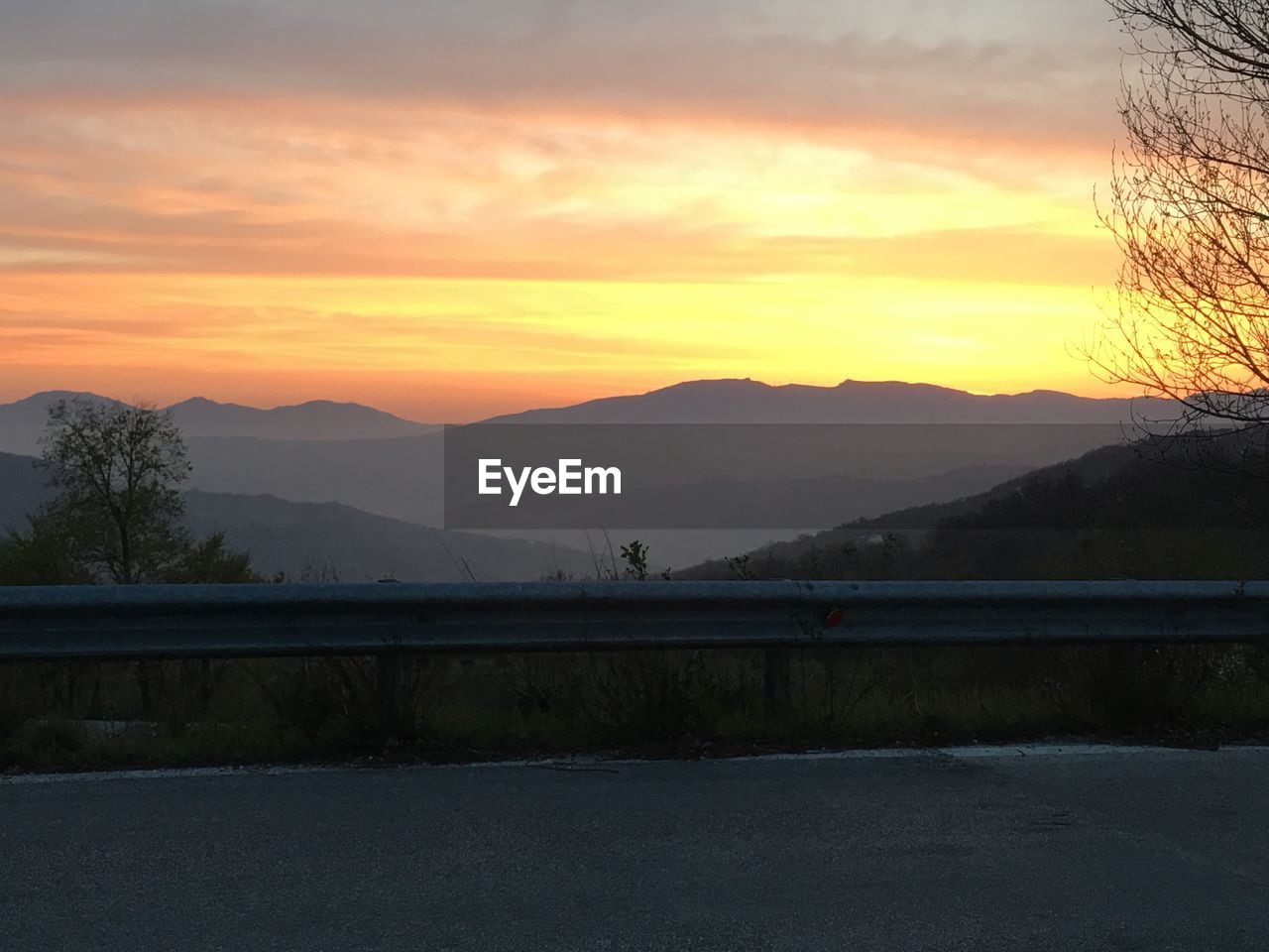 SILHOUETTE TREES BY MOUNTAINS AGAINST SKY DURING SUNSET