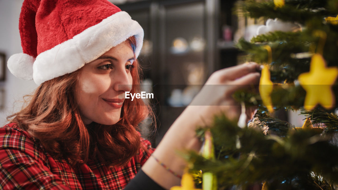 Young beautiful girl prepares christmas tree in the house