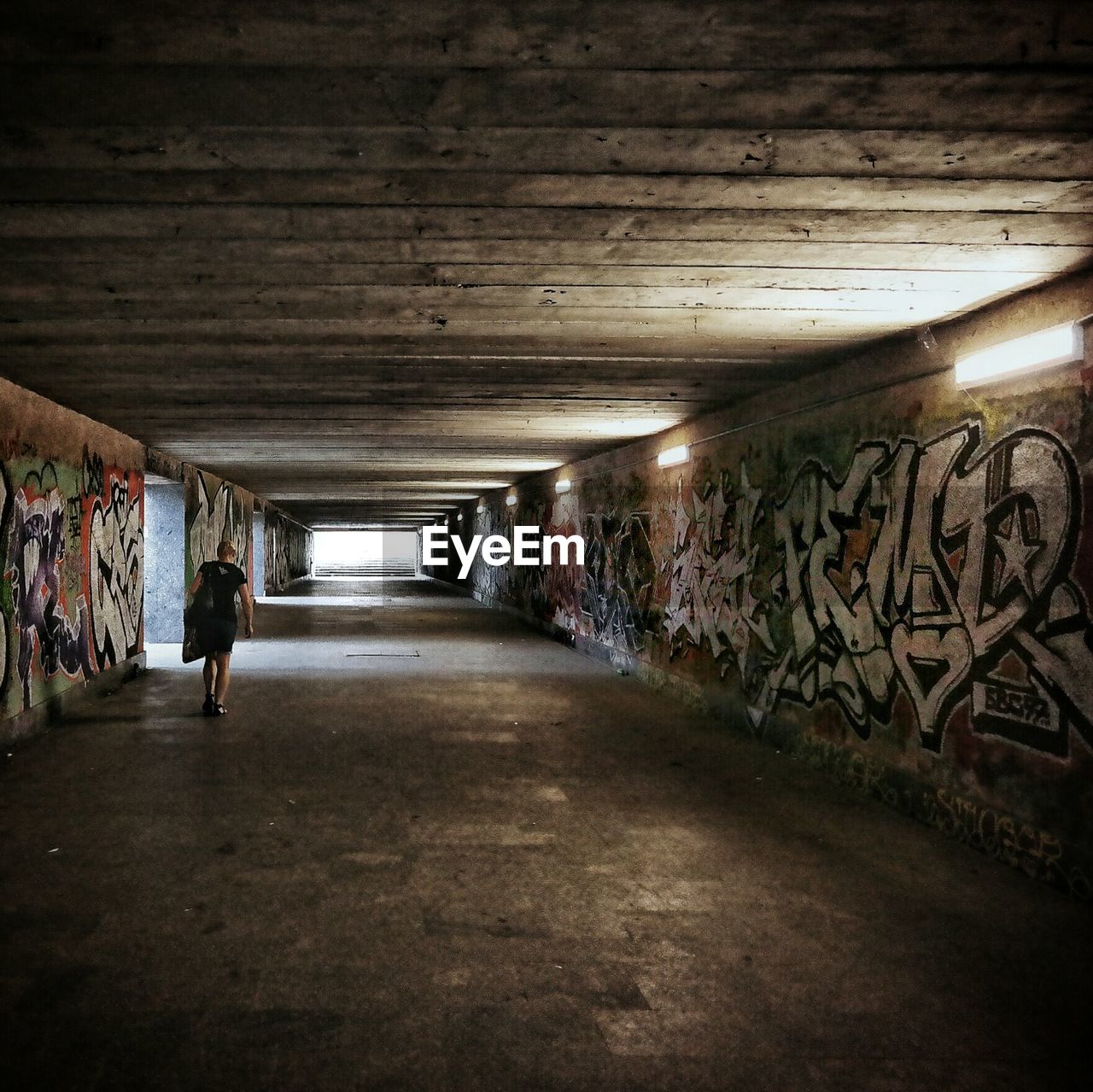 Rear view of woman walking in illuminated tunnel