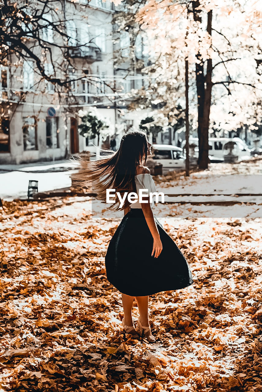 FULL LENGTH REAR VIEW OF WOMAN STANDING AGAINST TREES