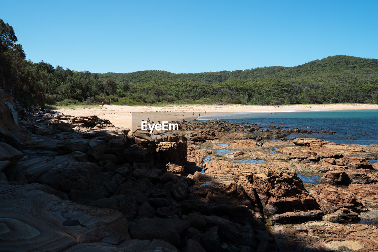 SCENIC VIEW OF ROCKS ON BEACH AGAINST CLEAR SKY