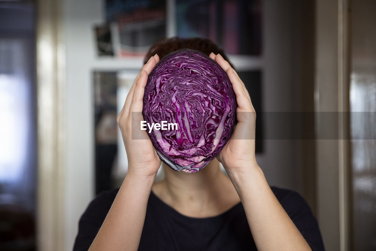 Woman holding a red cabbage in front of her face
