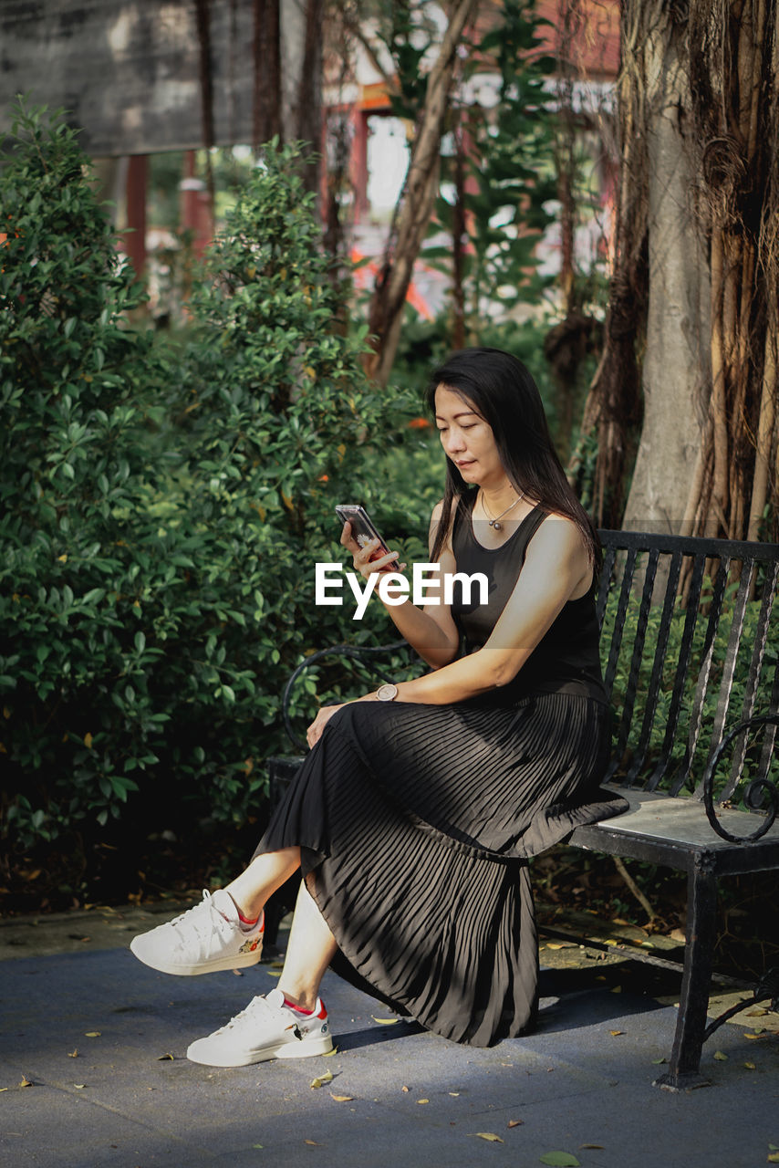 Young woman sitting on bench in park