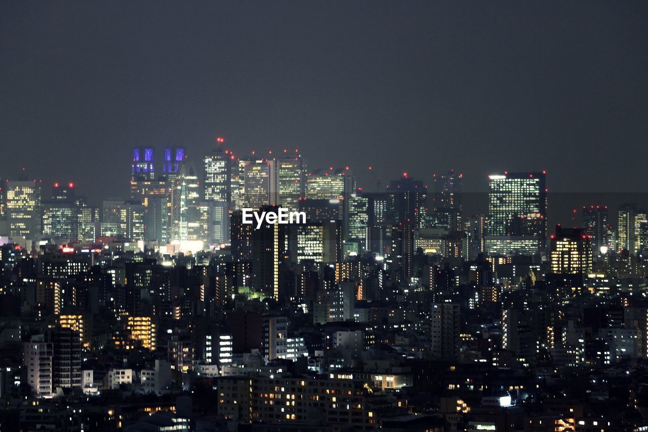 Illuminated cityscape against sky at night