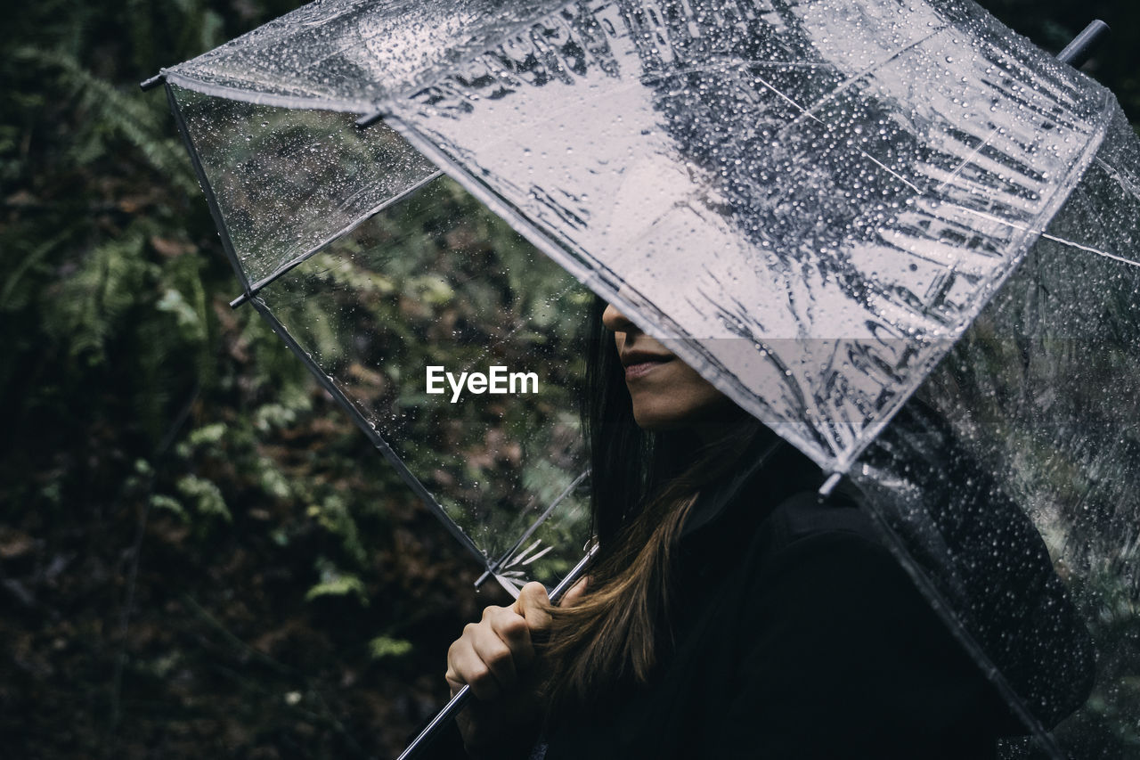 Close-up of woman holding umbrella during rain