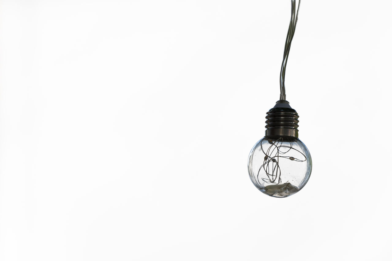 Close -up of light bulb hanging against white background