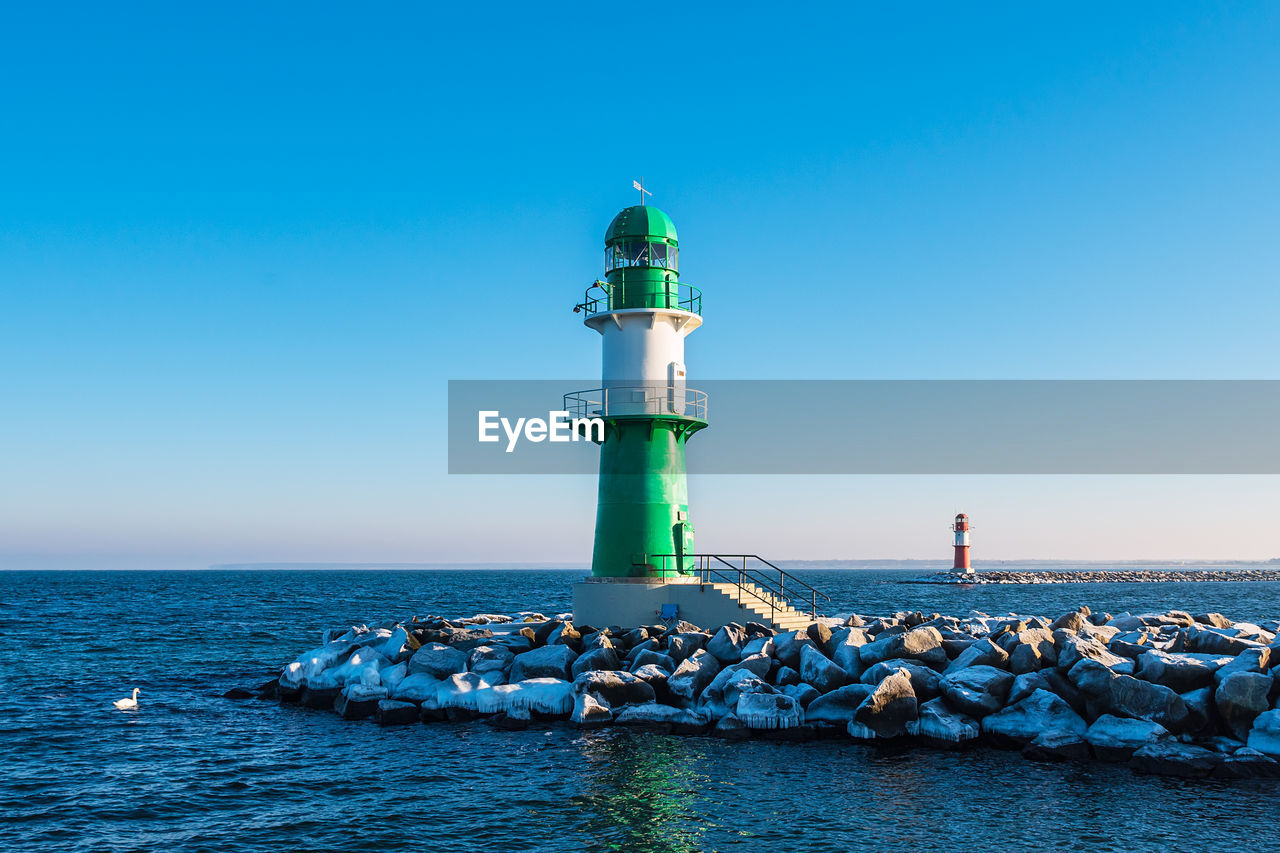 Lighthouse by sea against sky