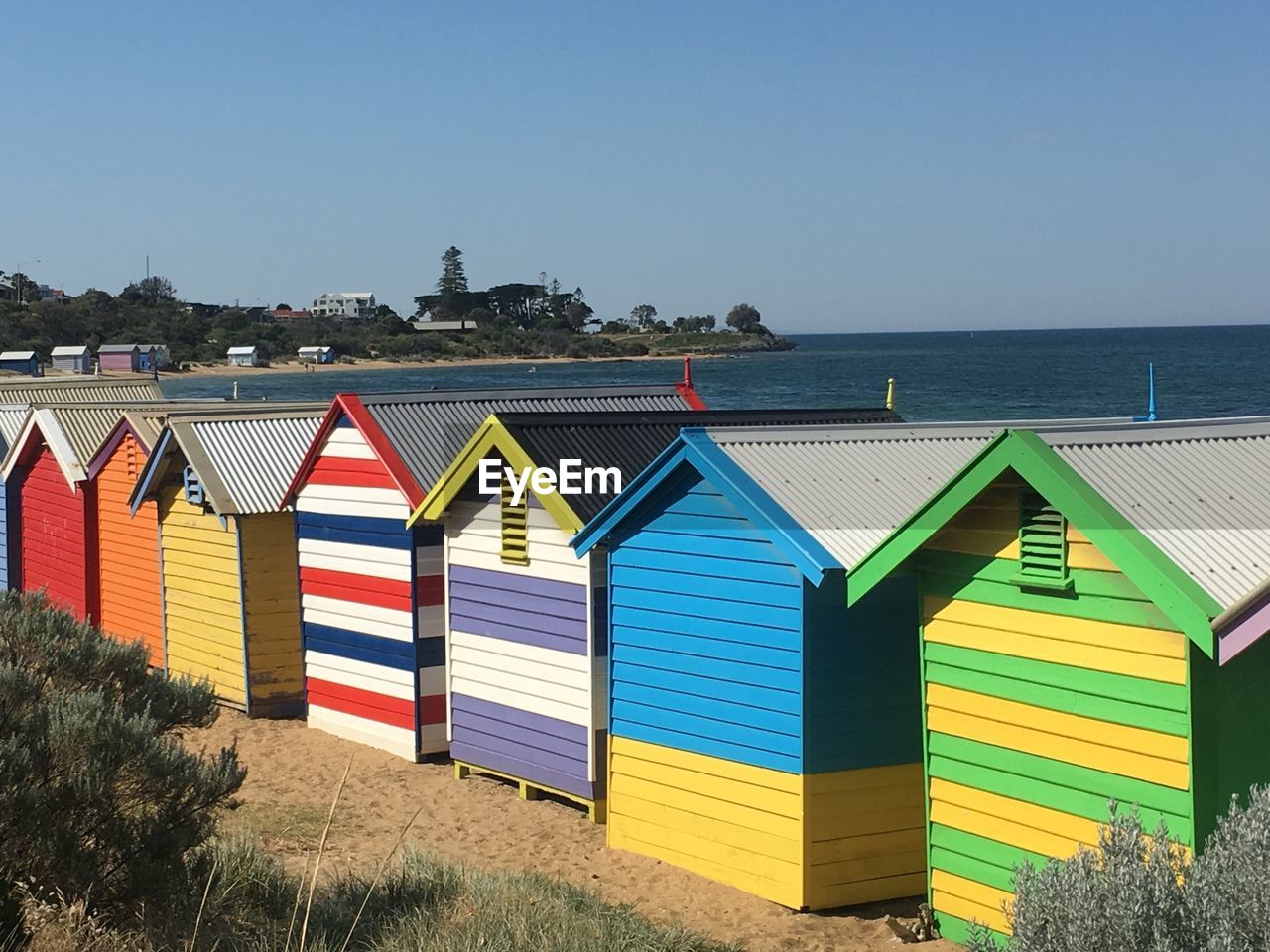 MULTI COLORED FLAGS ON BEACH AGAINST CLEAR BLUE SKY