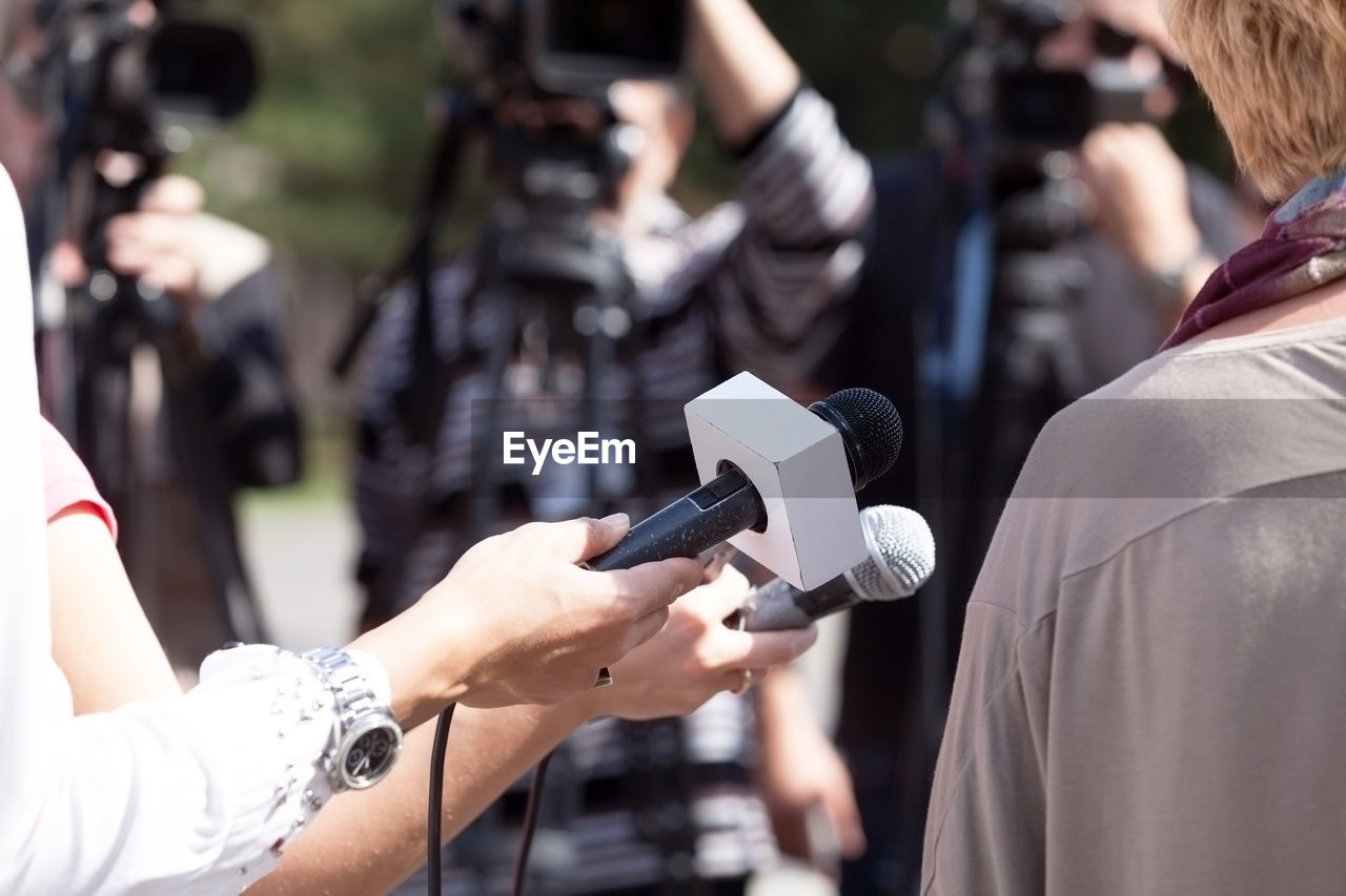 Cropped image of journalists interviewing woman
