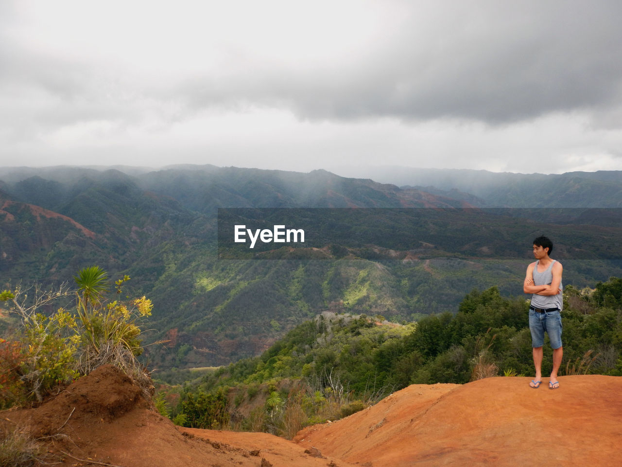 REAR VIEW OF MAN LOOKING AT MOUNTAINS AGAINST SKY