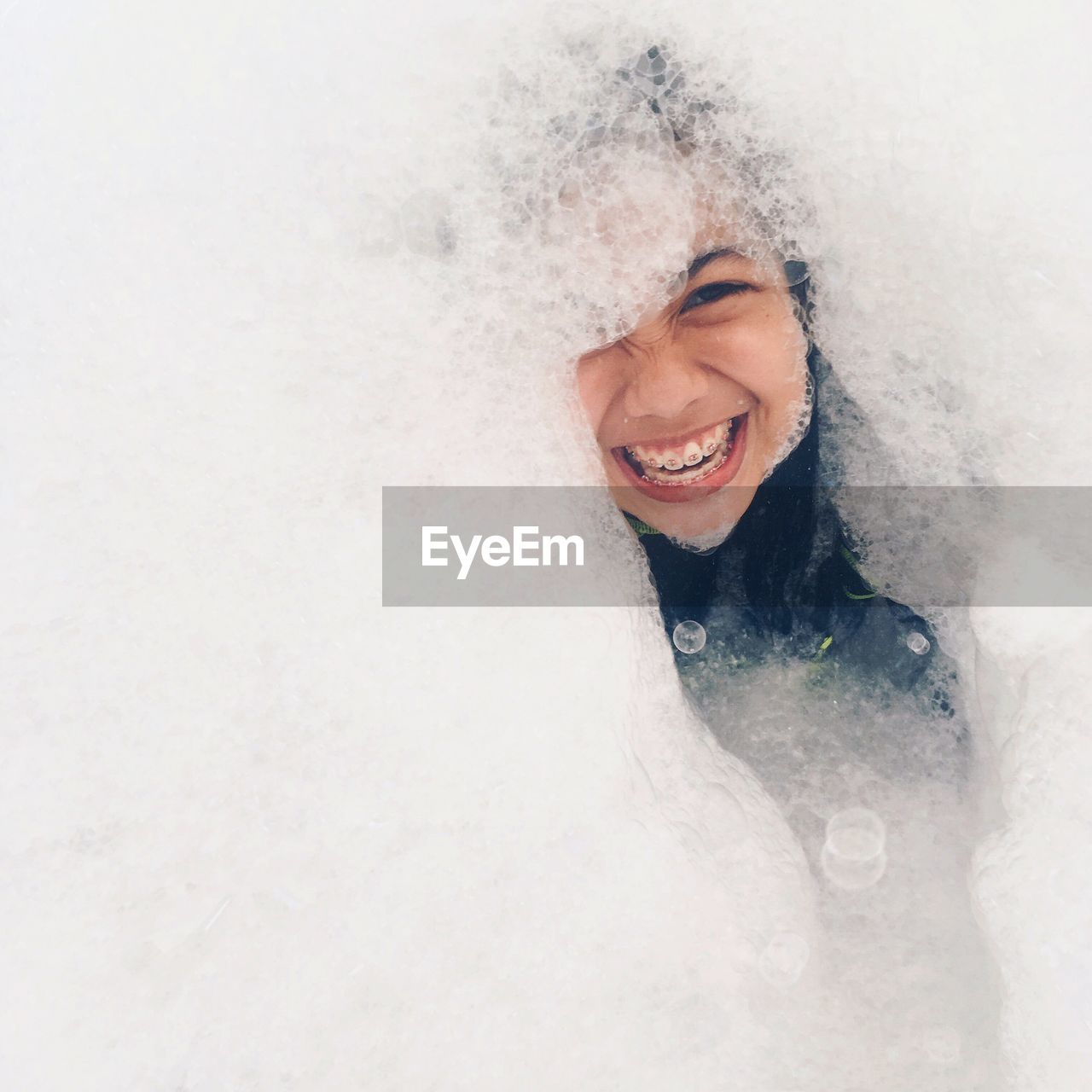 PORTRAIT OF SMILING YOUNG WOMAN WITH SNOW