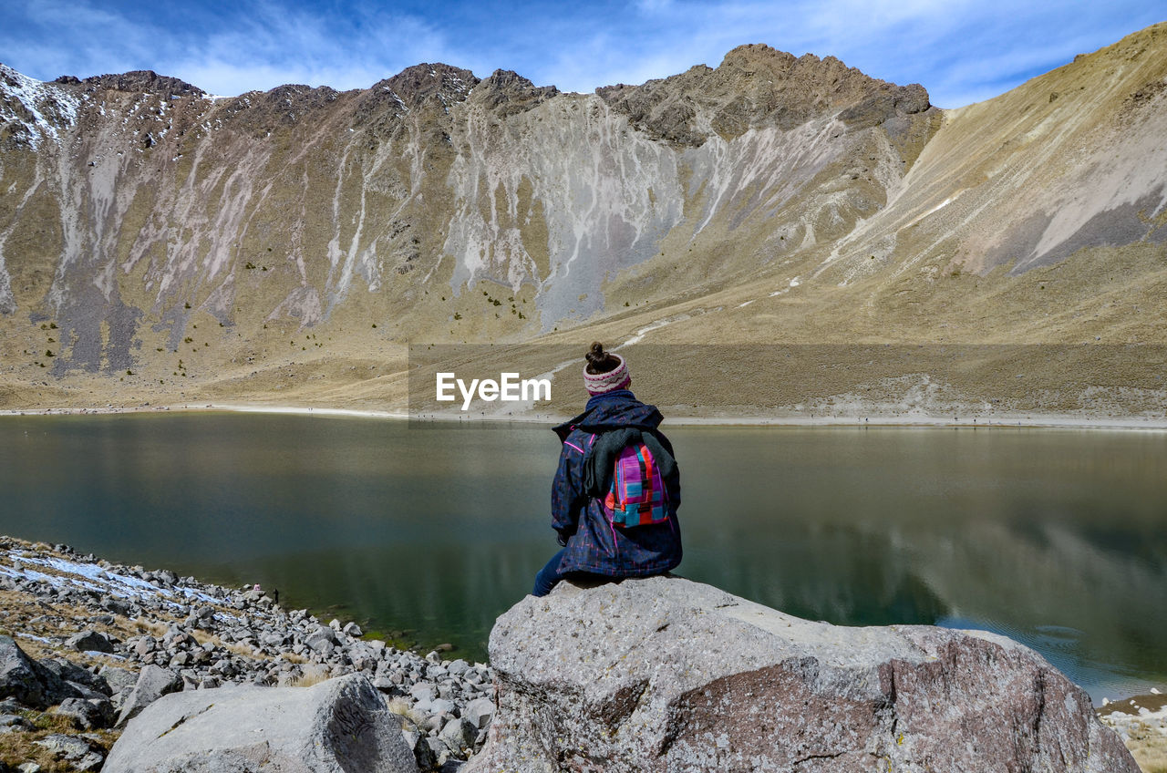 FULL LENGTH OF MAN ON ROCKS AGAINST MOUNTAINS