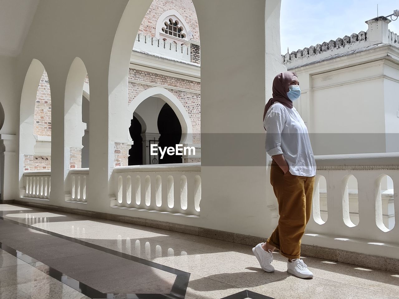 Rear view of woman standing against white building