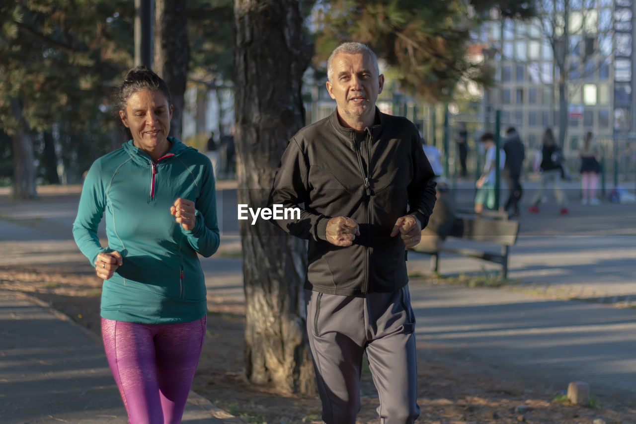 Happy mature couple running and exercising in a park outdoors