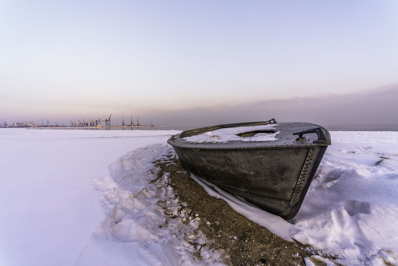 FROZEN BOAT ON SNOWCAPPED MOUNTAINS AGAINST SKY