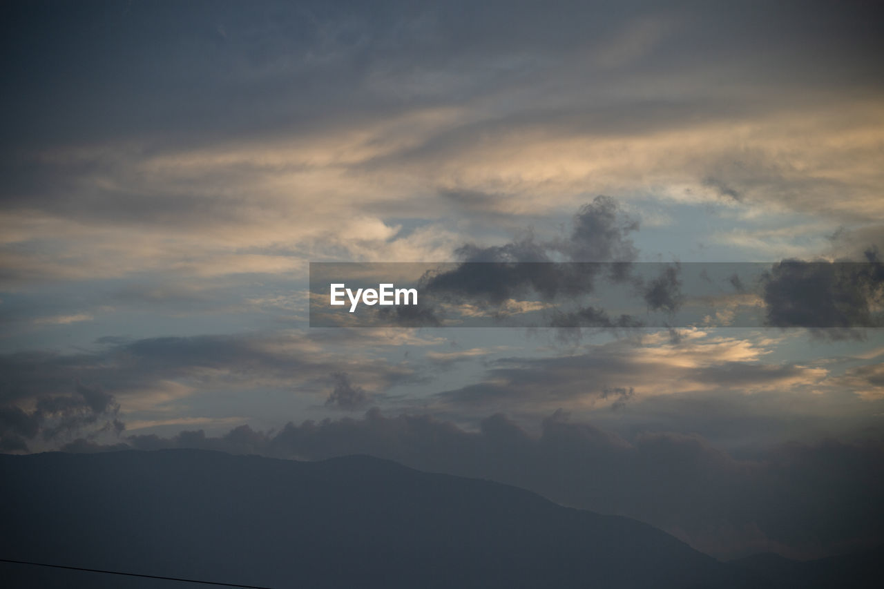 LOW ANGLE VIEW OF DRAMATIC SKY OVER SILHOUETTE MOUNTAINS