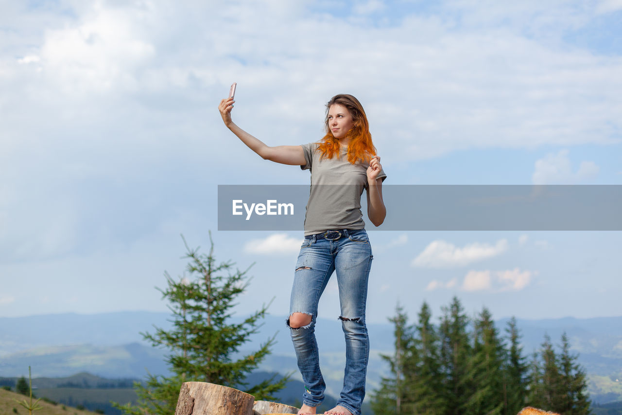 Girl makes selfie on a smartphone against the background of the carpathian mountains