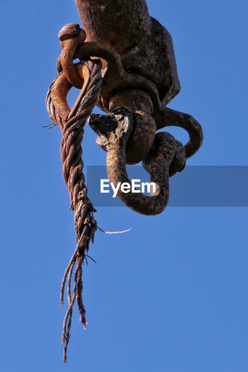 LOW ANGLE VIEW OF CHAIN TIED UP ON METAL AGAINST BLUE SKY