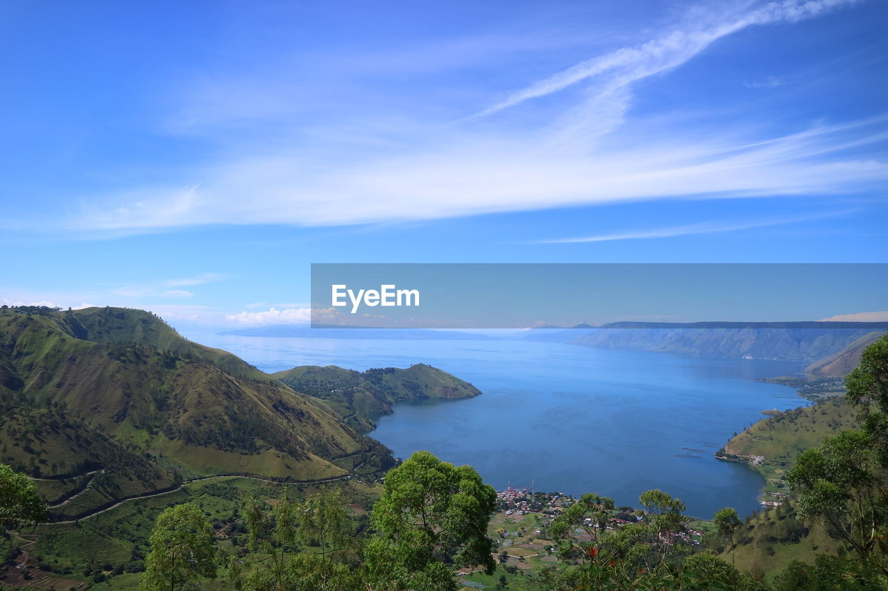 Scenic view of sea and mountains against blue sky