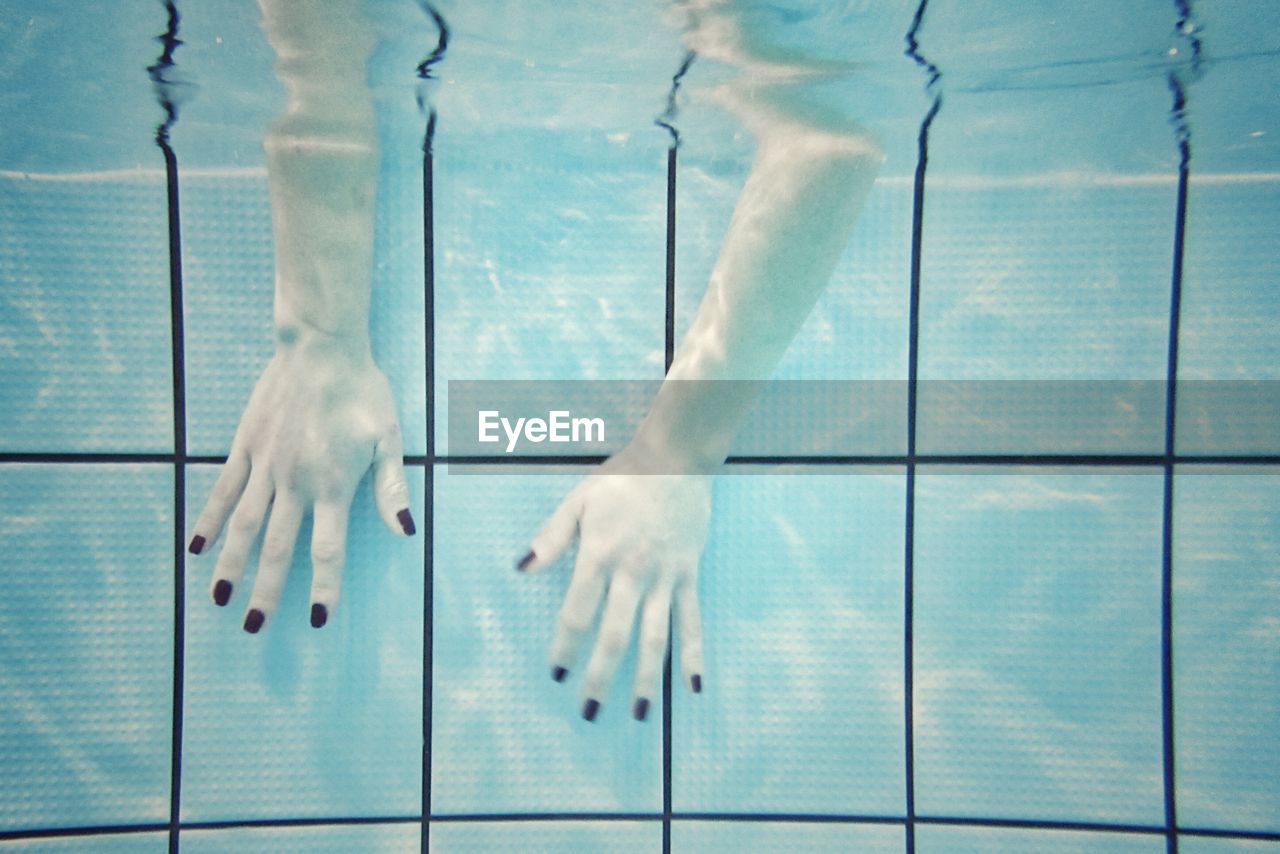 Close-up of hands with nail polish dipped in swimming pool