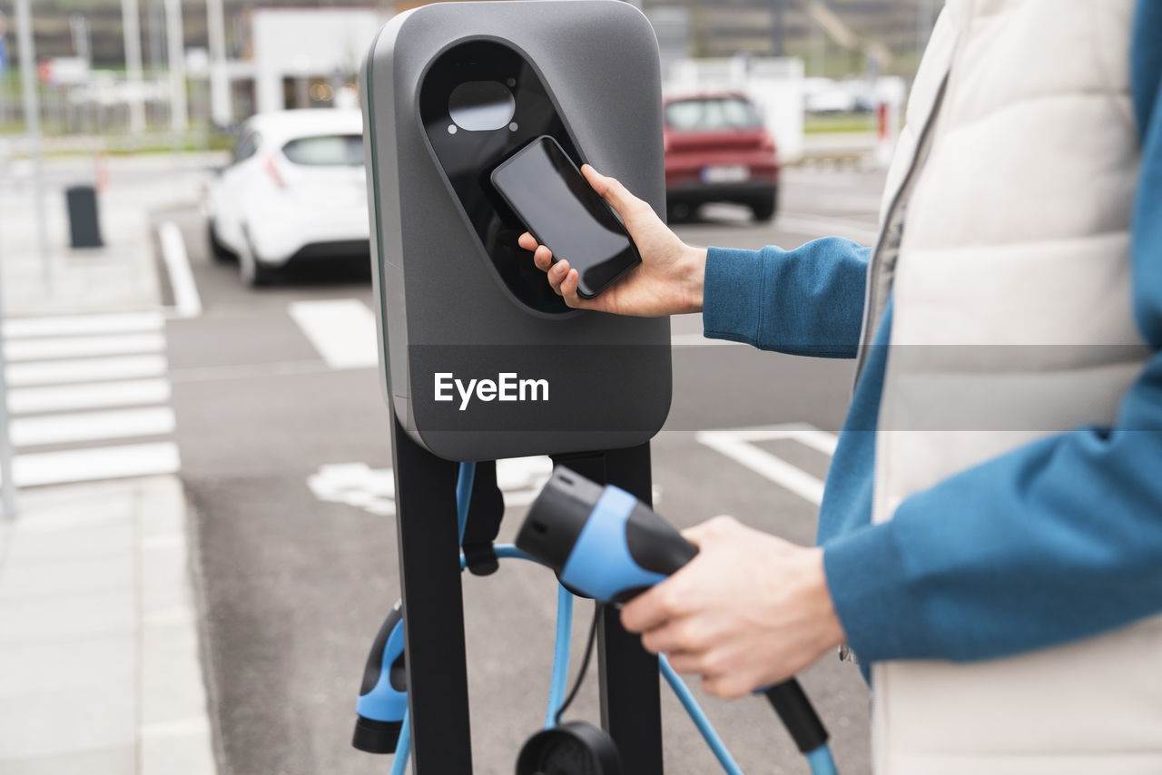 Man scanning and paying through smart phone at charging station