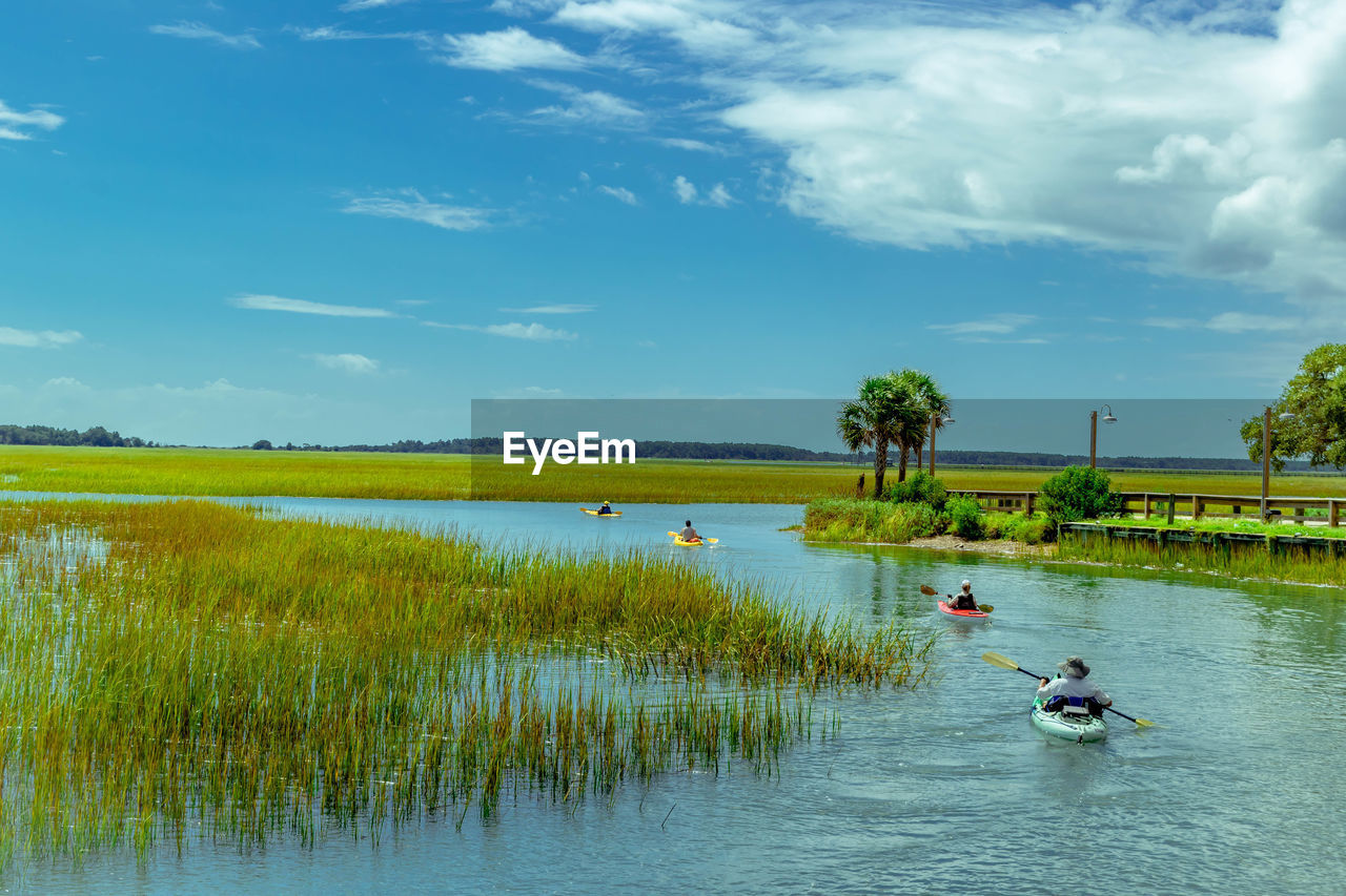 People kayaking in lake against sky