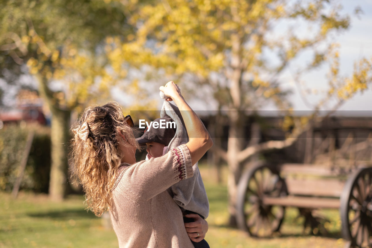 Portrait of mother warming her baby outdoors