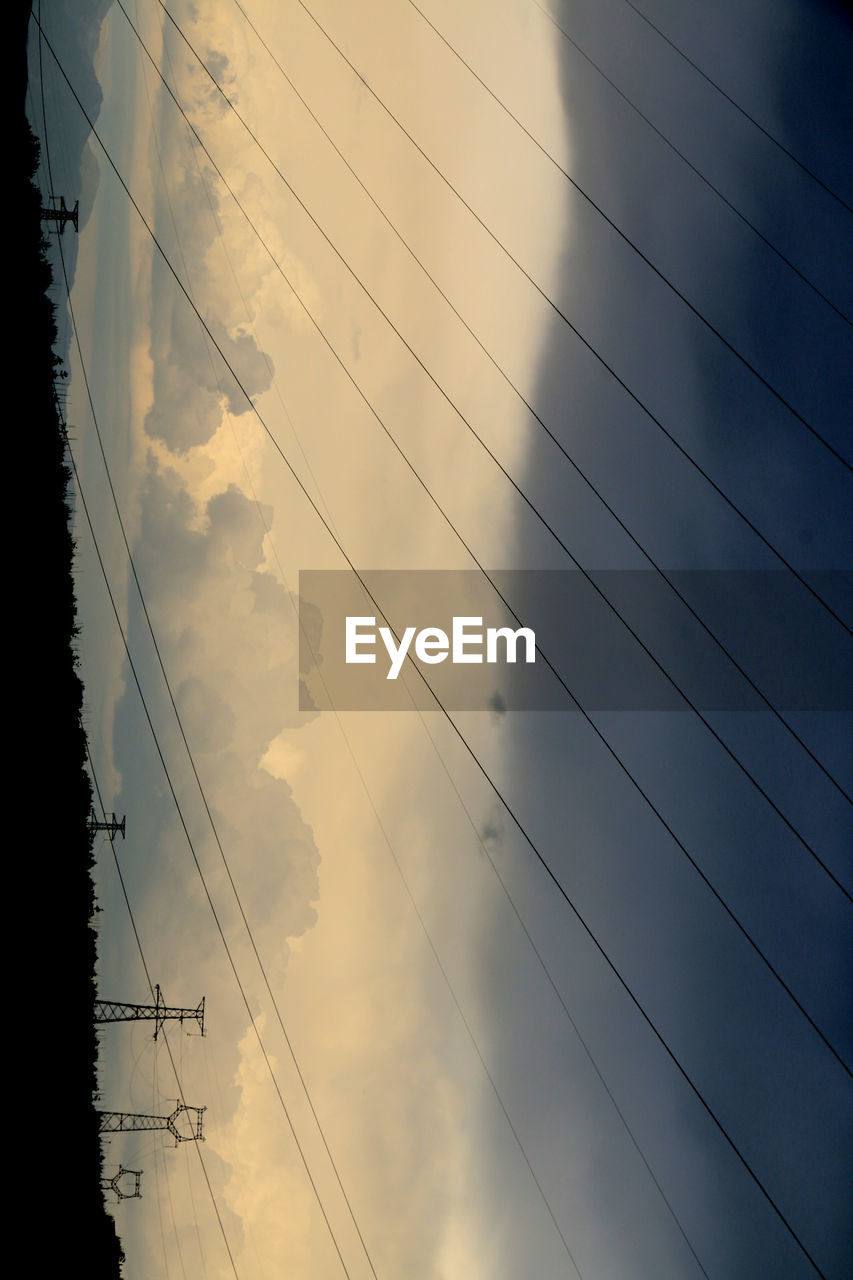 LOW ANGLE VIEW OF POWER LINES AGAINST CLOUDY SKY