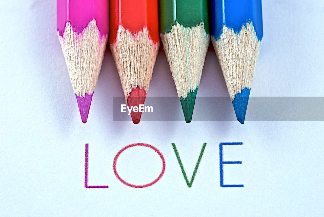 Close-up of love text with colored pencils on white background