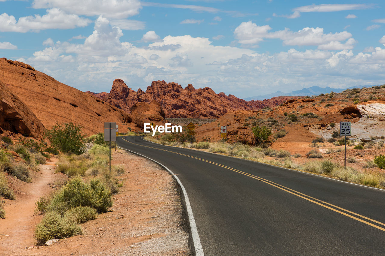 Road leading towards mountains against sky