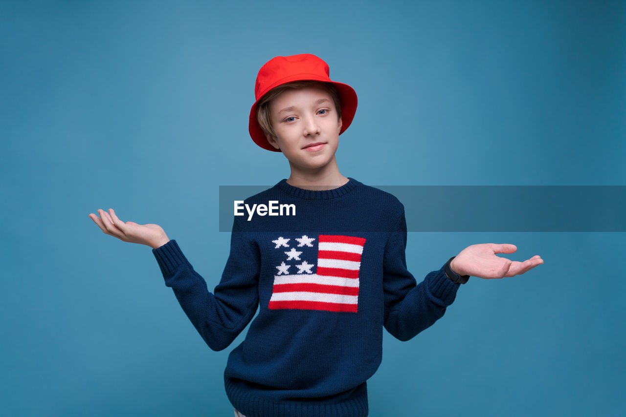 Smiling cheerful young guy in red panama hat and blue sweater with us flag