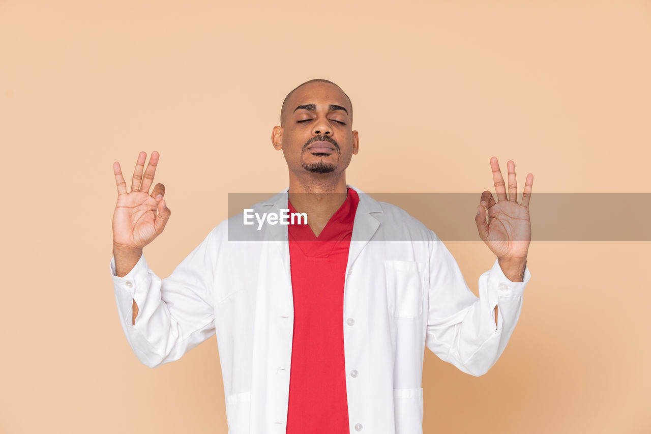 YOUNG MAN LOOKING AT CAMERA AGAINST GRAY BACKGROUND