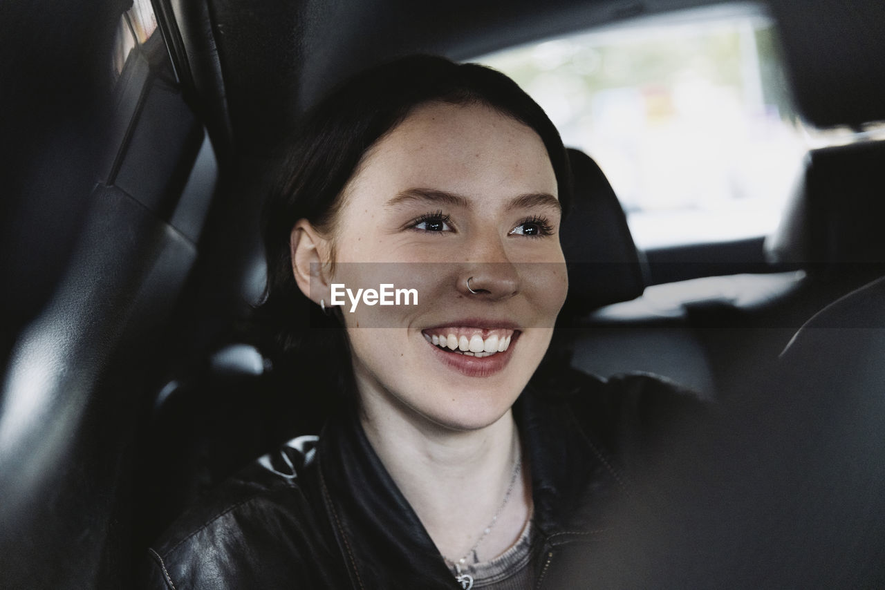 Smiling woman wearing nose ring sitting in car on vacation