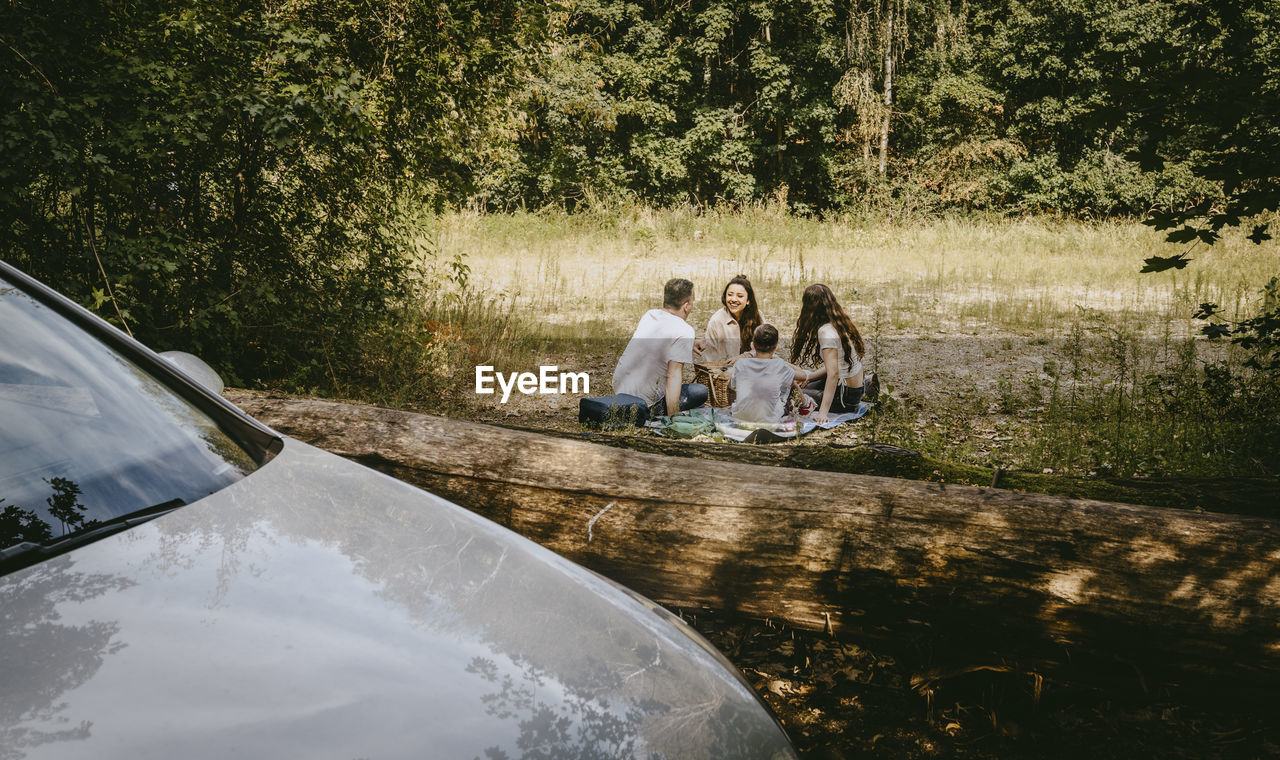 Family spending leisure time while sitting in forest during vacation