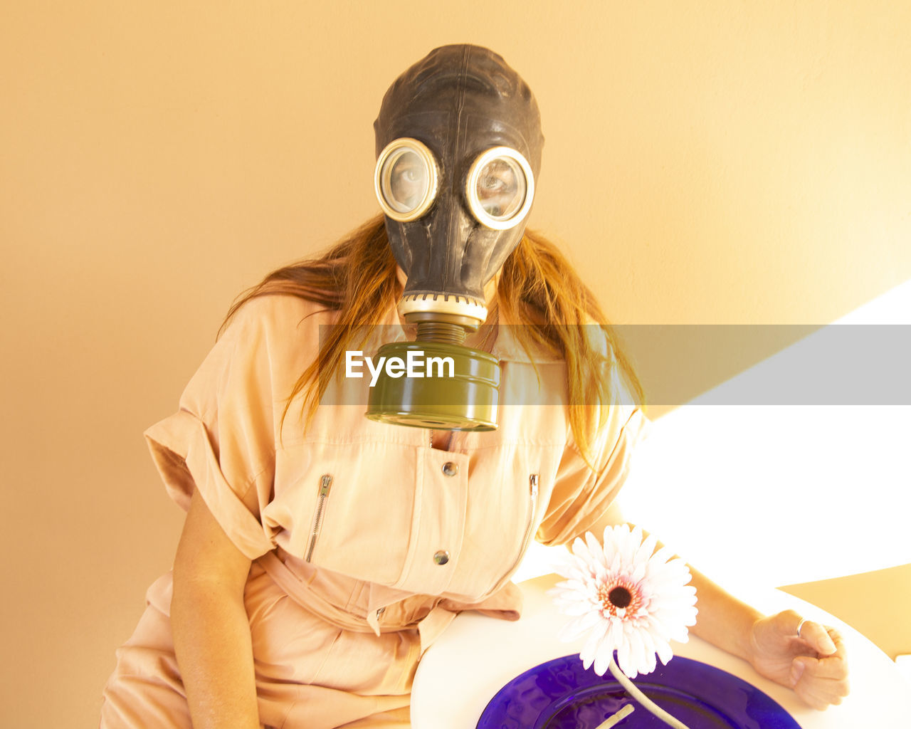 Portrait of woman wearing gas mask against wall