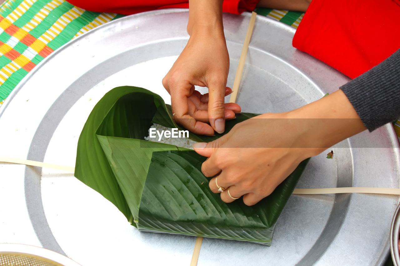 Midsection of woman wrapping food in leaves on tray