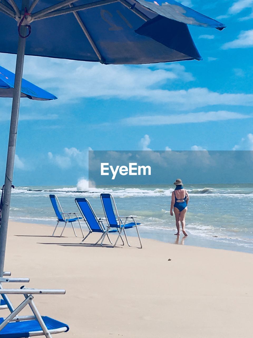 FULL LENGTH OF MAN STANDING ON BEACH AGAINST SKY