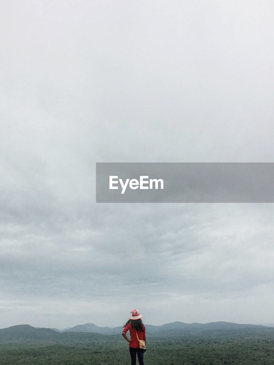 Rear view of woman standing against cloudy sky