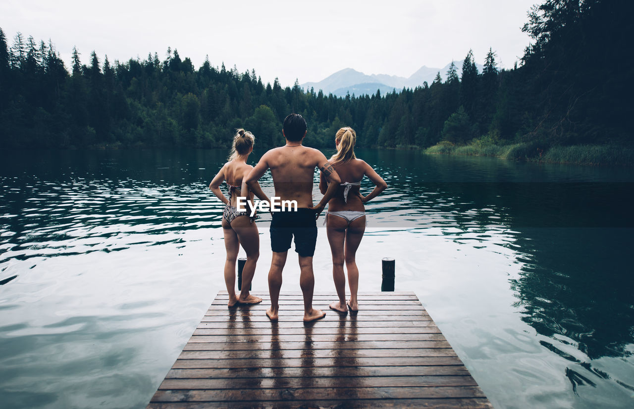 REAR VIEW OF PEOPLE STANDING ON LAKE