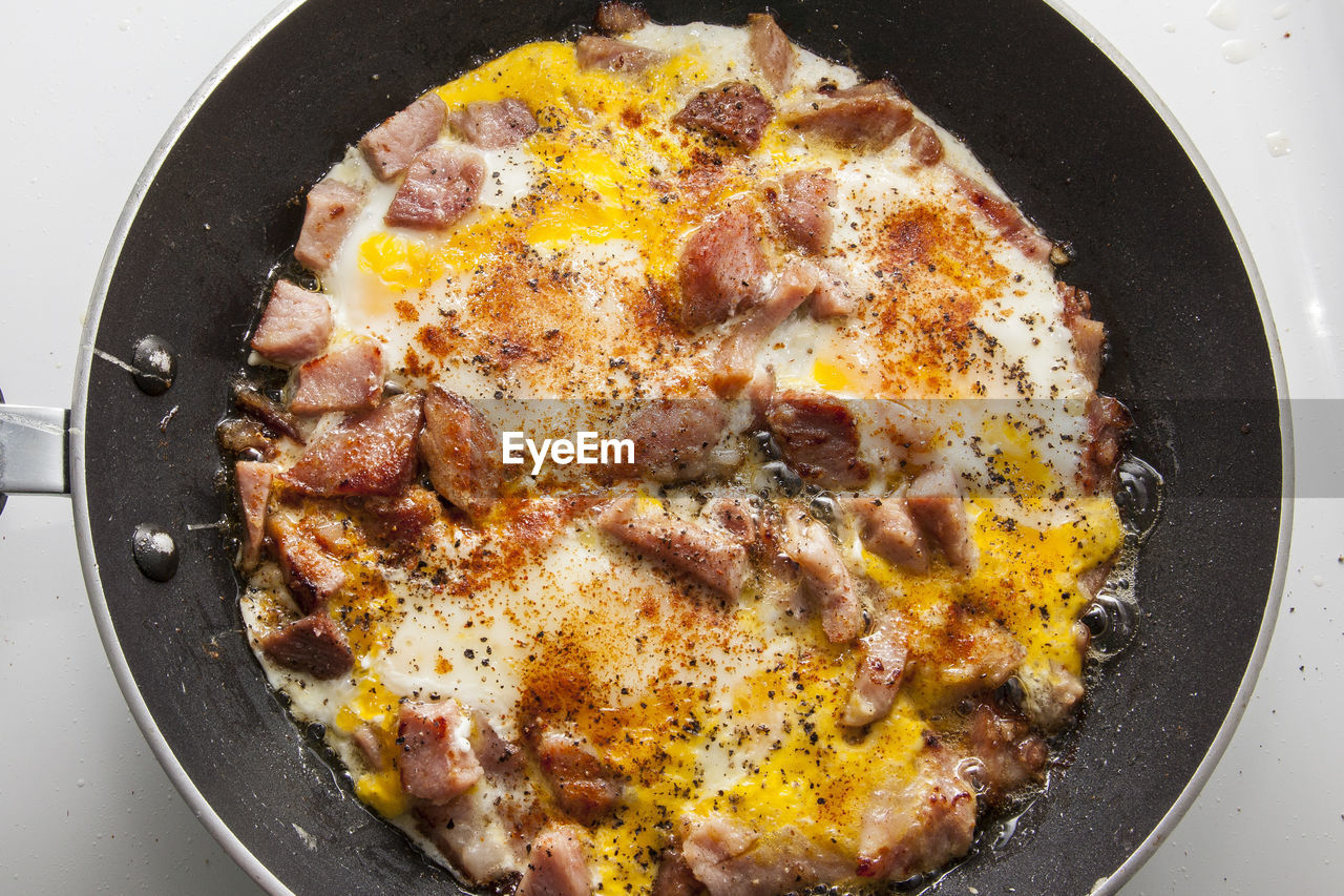 High angle view of ham and egg in frying pan on table at home