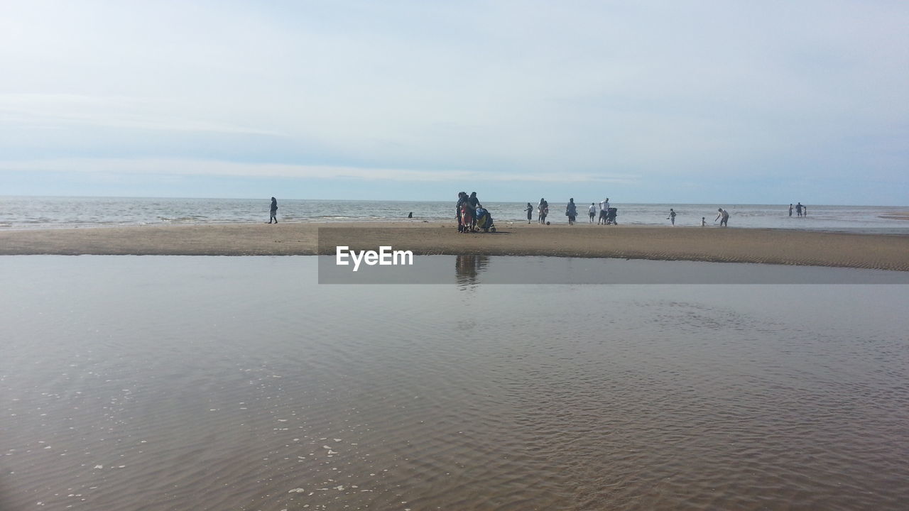 People at beach against cloudy sky