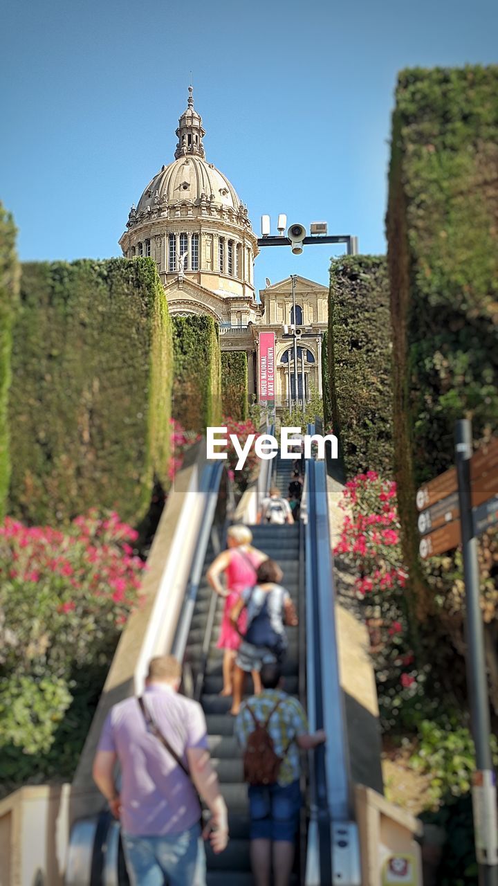 People standing on escalator leading towards national art museum of catalonia