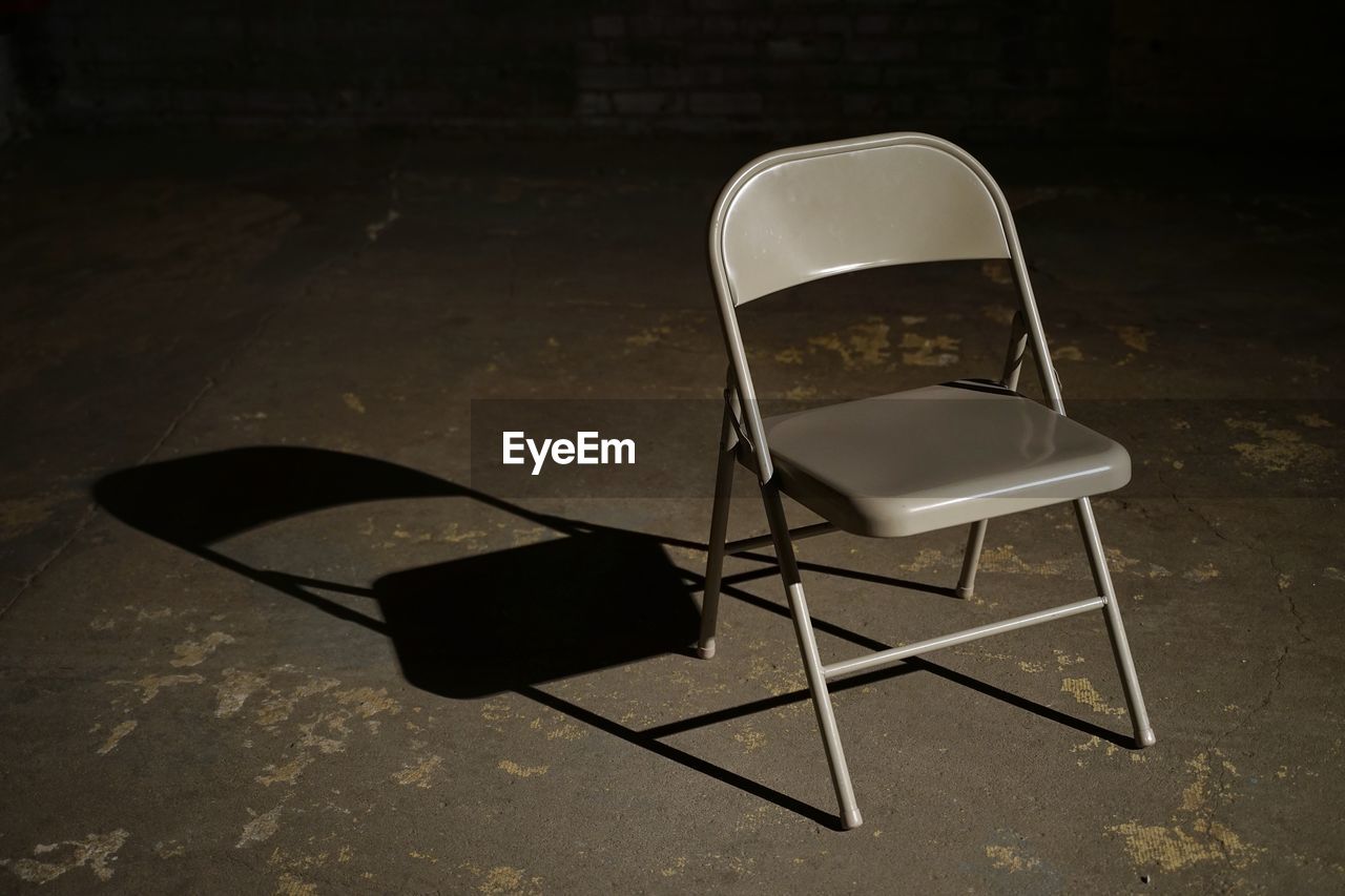 High angle view of empty chair on floor with shadow