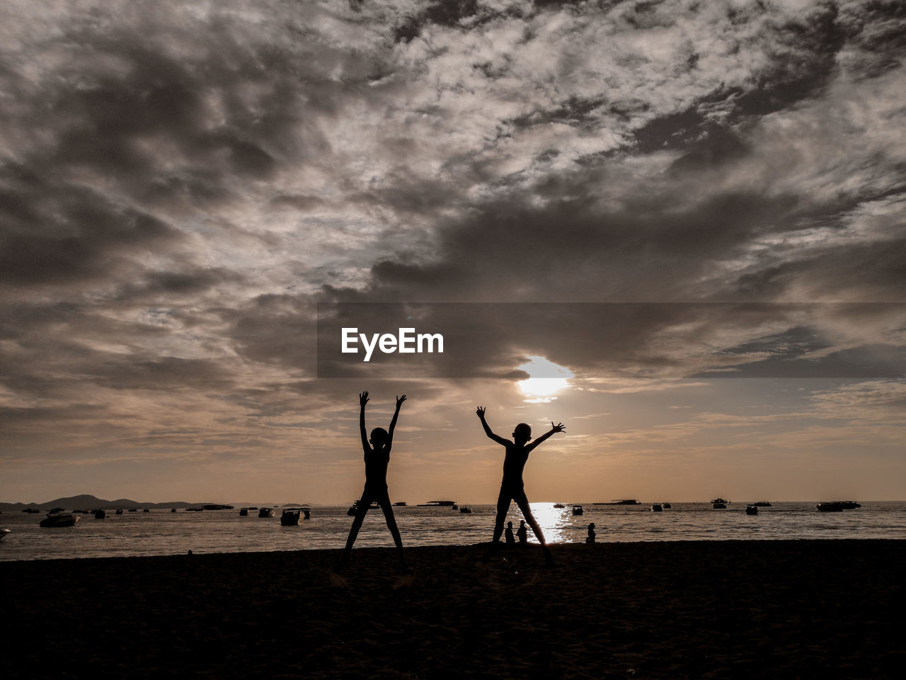 SILHOUETTE PEOPLE STANDING ON BEACH AGAINST SUNSET SKY