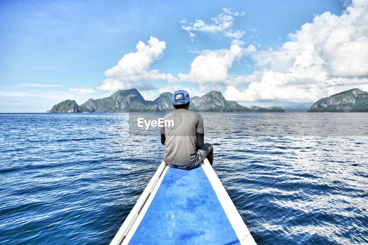 REAR VIEW OF MAN IN BOAT SAILING ON SEA