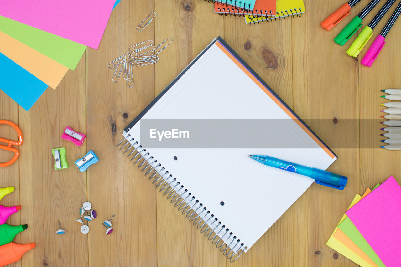 Directly above shot of open book with art equipment on table