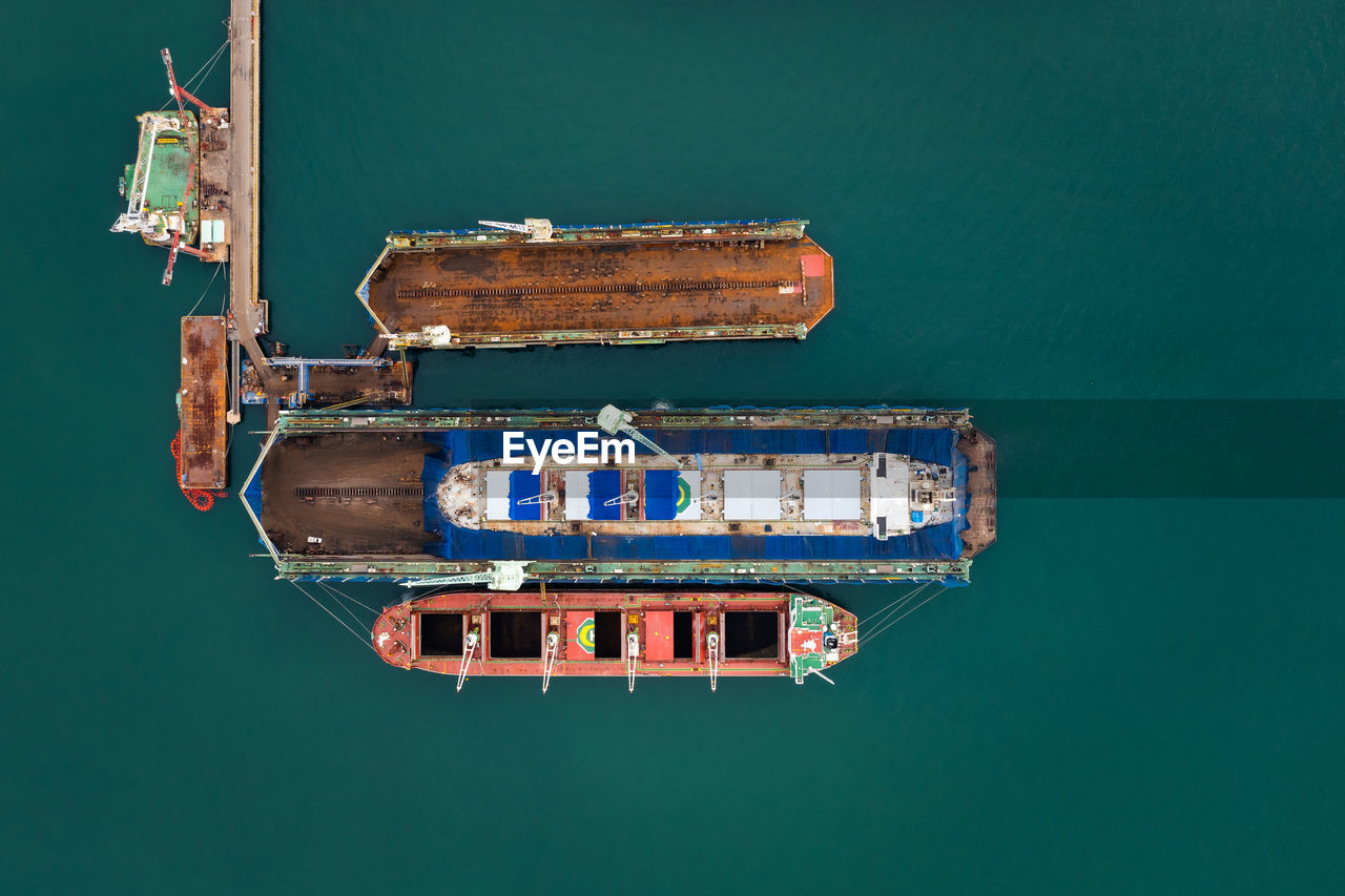 Aerial top view container oil ship in shipyard for repair and maintenance in green sea