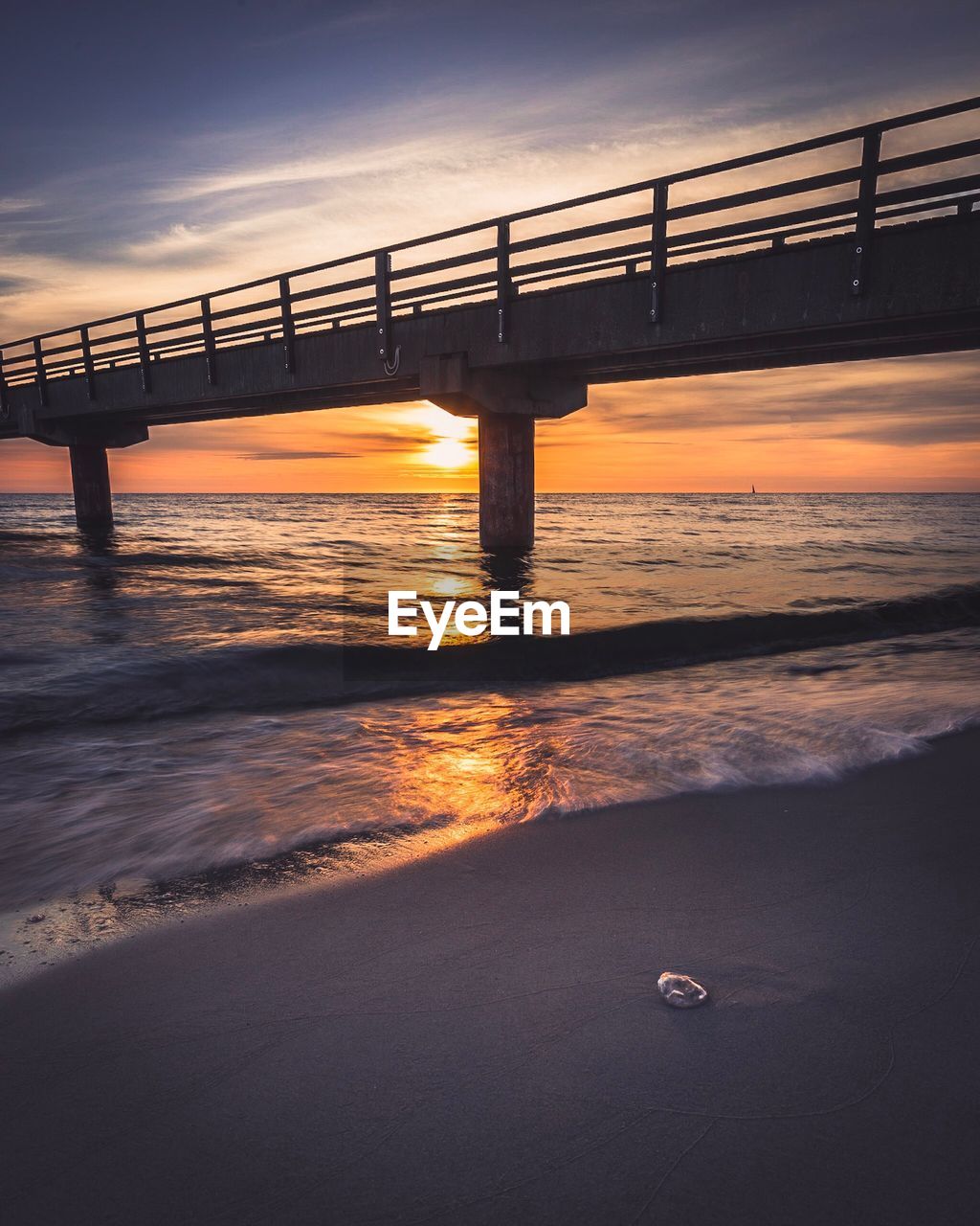 Bridge over sea against sky during sunset