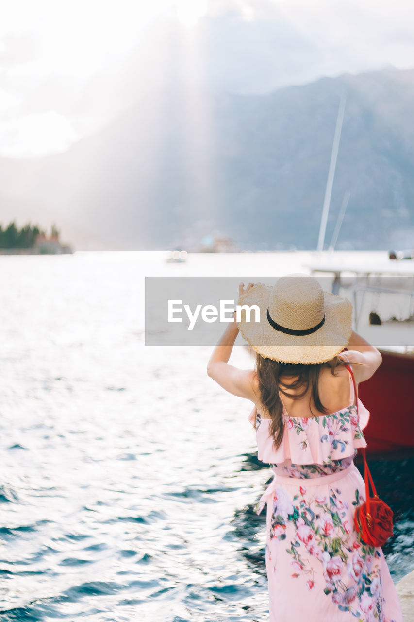 WOMAN WEARING HAT AGAINST SEA